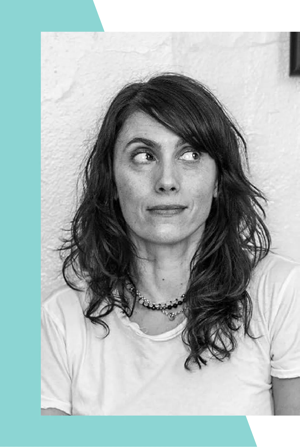 A black and white portrait of a woman with long, wavy hair and a necklace.